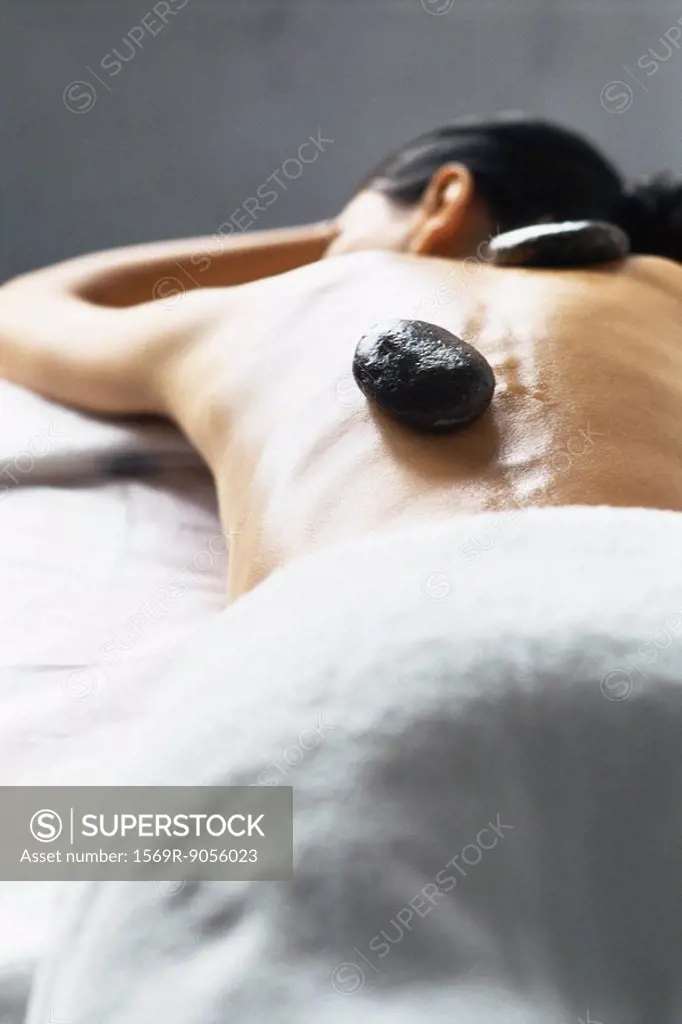 Lastone therapy, woman lying on stomach with stone placed on bare back