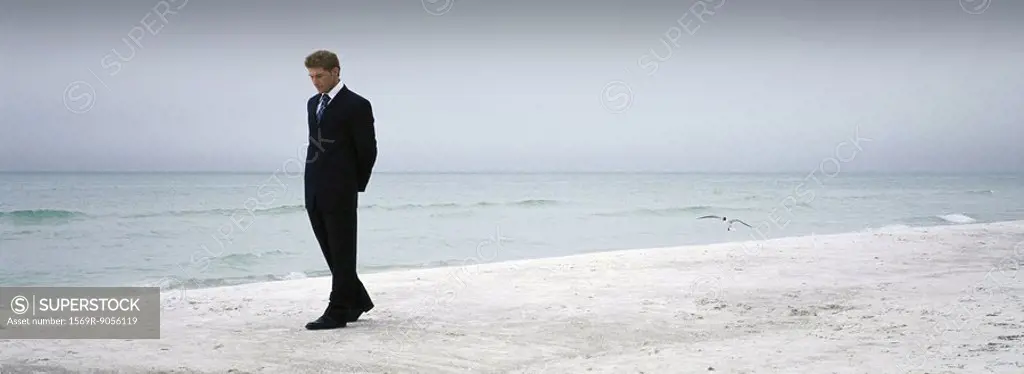 Man in suit walking on beach