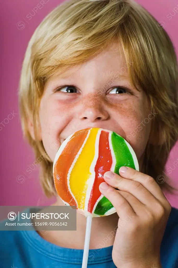 Boy holding large lollipop in front of face