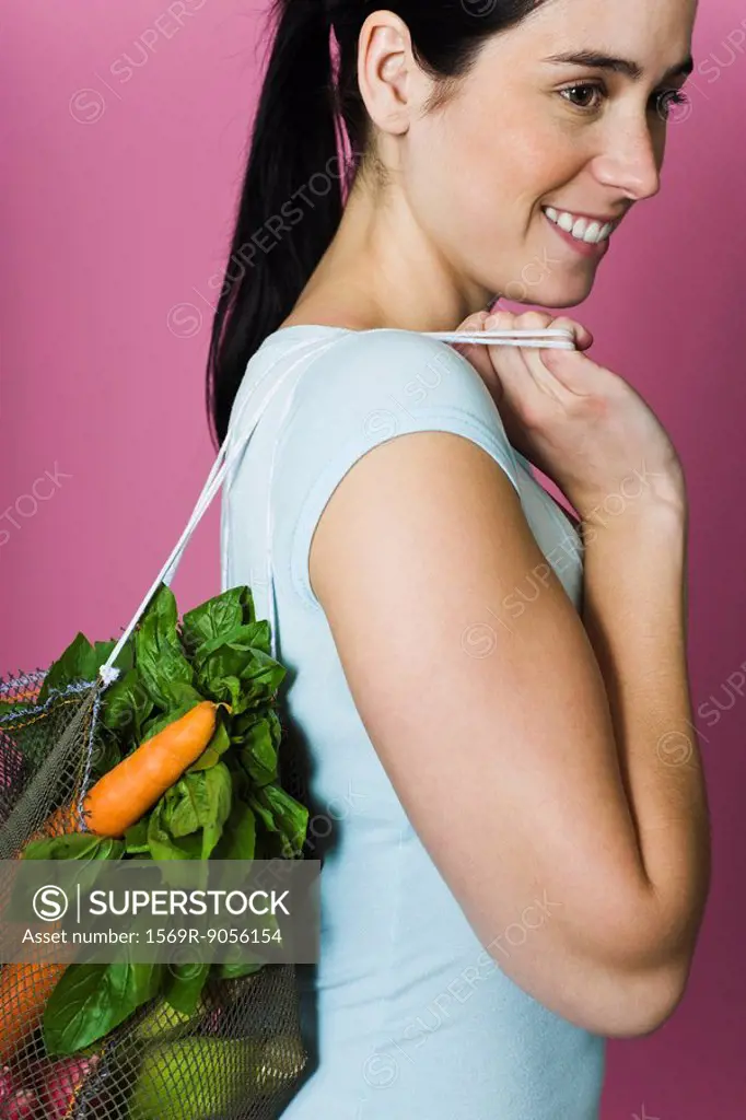 Young woman with sack of fresh vegetables carried over shoulder