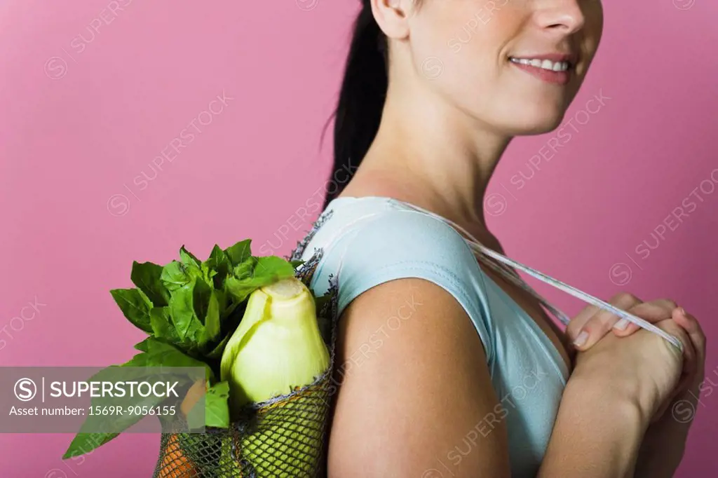 Woman with sack of fresh vegetables carried over shoulder