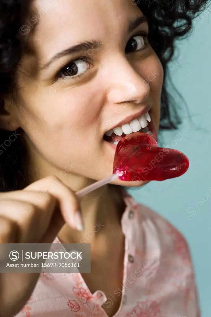Young woman eating heart_shaped lollipop