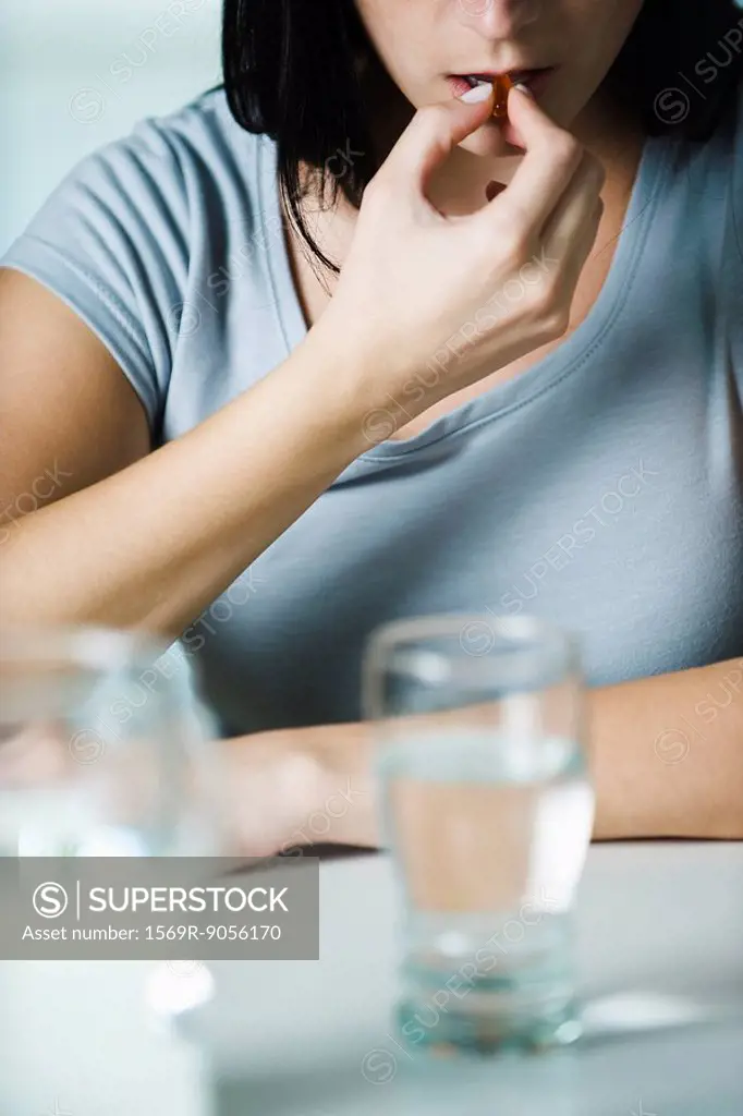 Woman taking vitamins, cropped