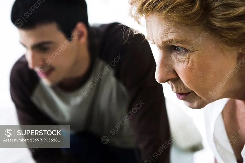 Senior woman looking intently, man in background