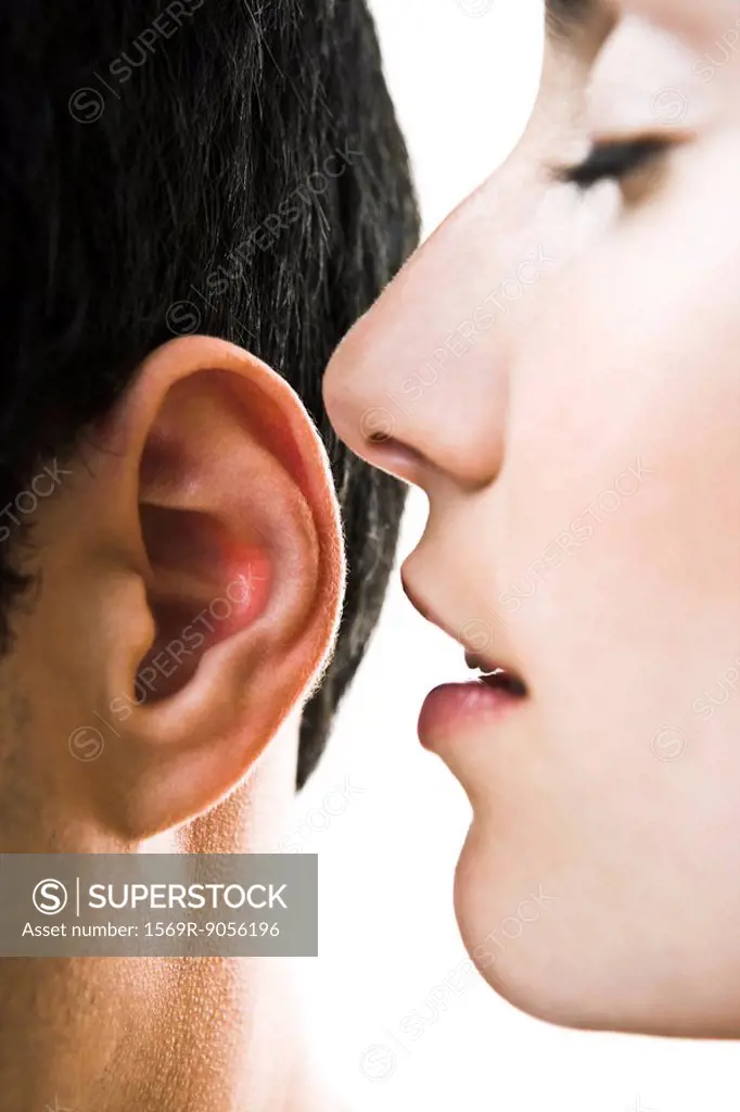 Woman with eyes closed whispering in man´s ear, close_up