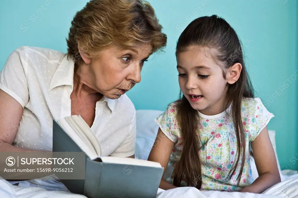 Little girl reading book with grandmother