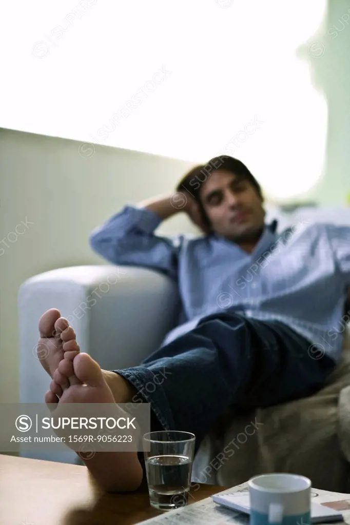 Man sitting on sofa with feet up on coffee table
