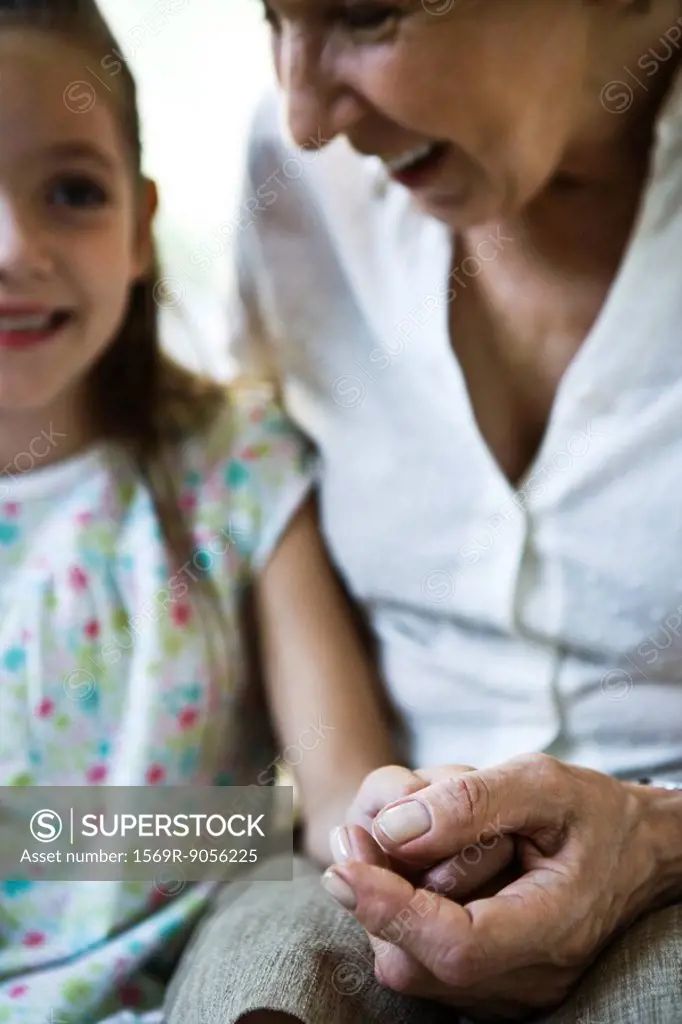 Grandmother and young granddaughter holding hands, close_up