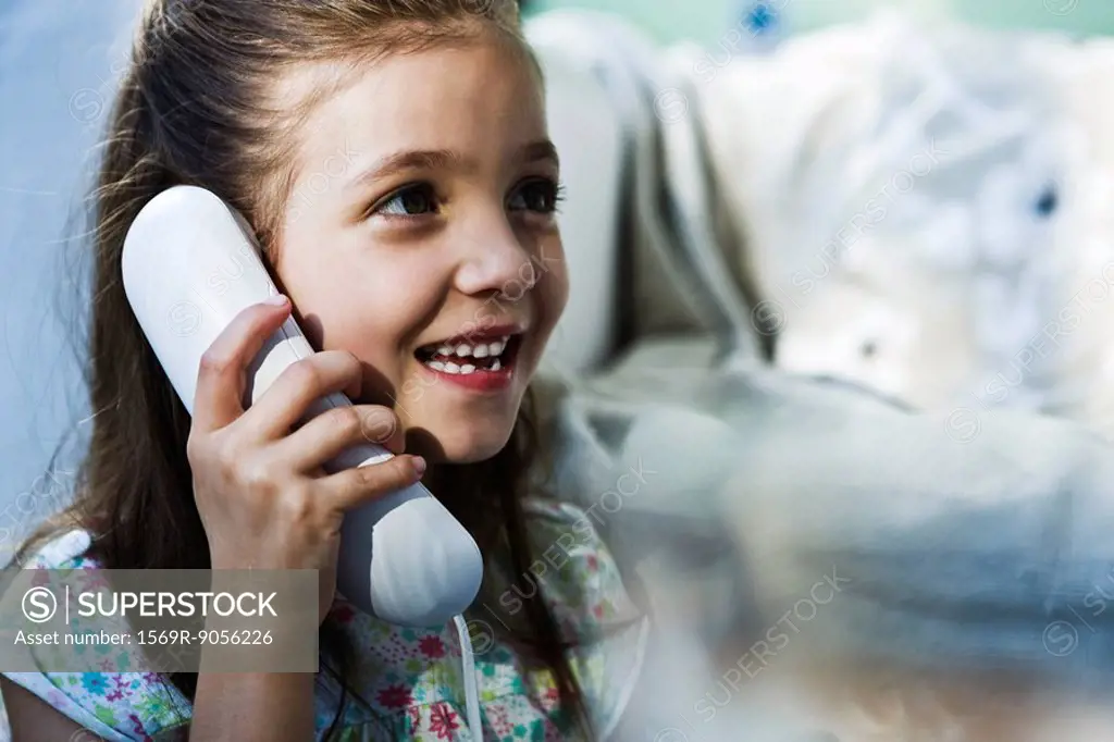 Little girl smiling using landline phone
