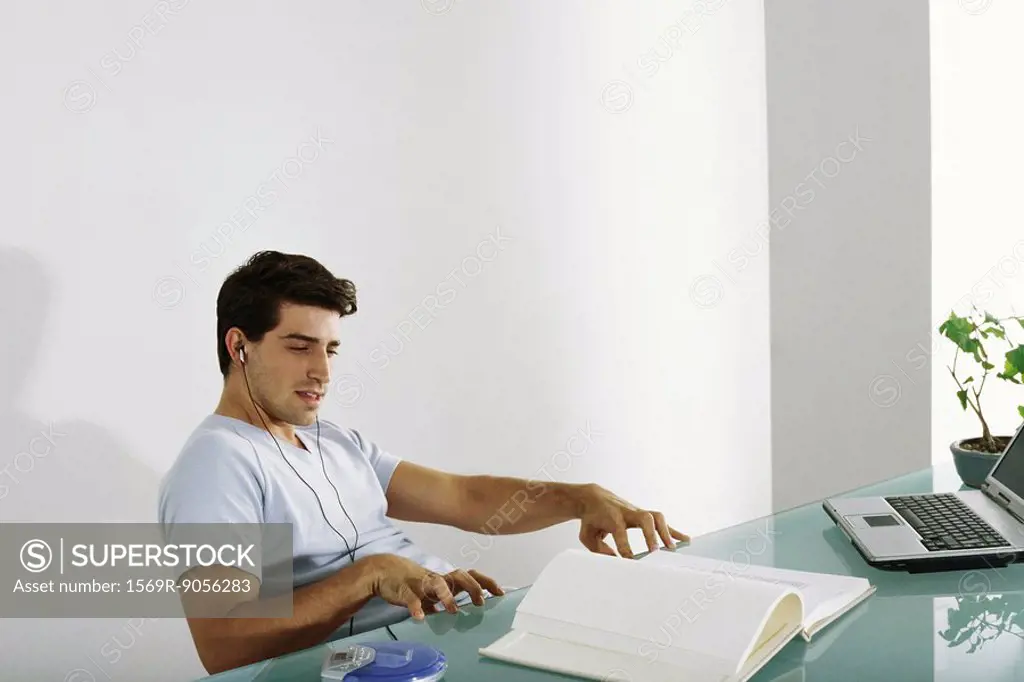 Man at desk listening to music, pretending to play piano along with song