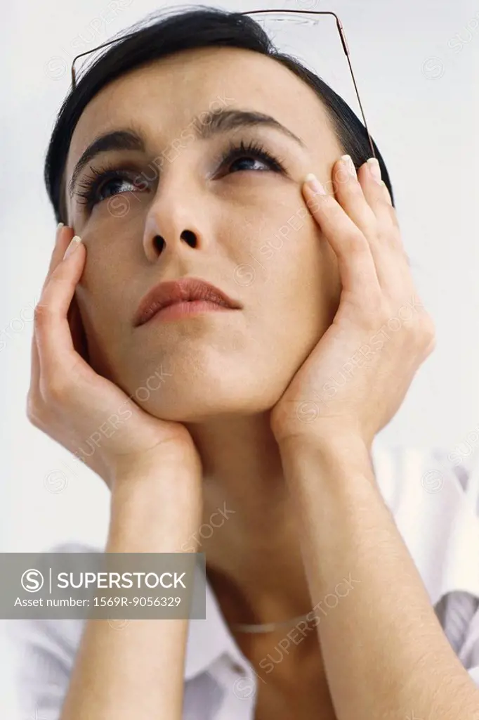 Woman holding head, looking up