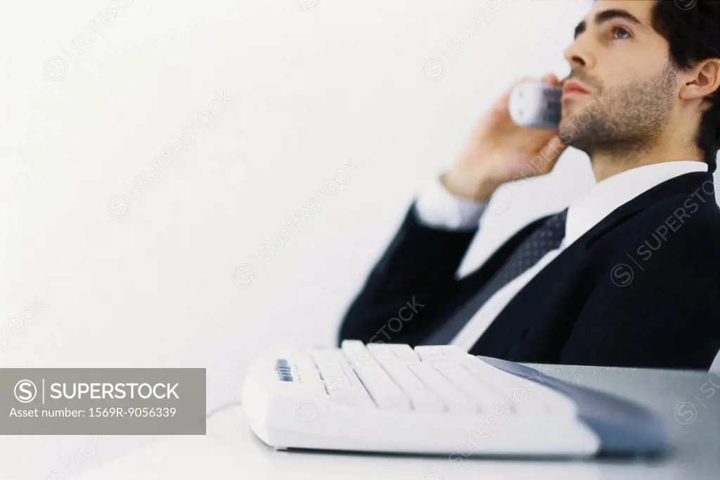 Businessman on phone call, leaning back, looking away