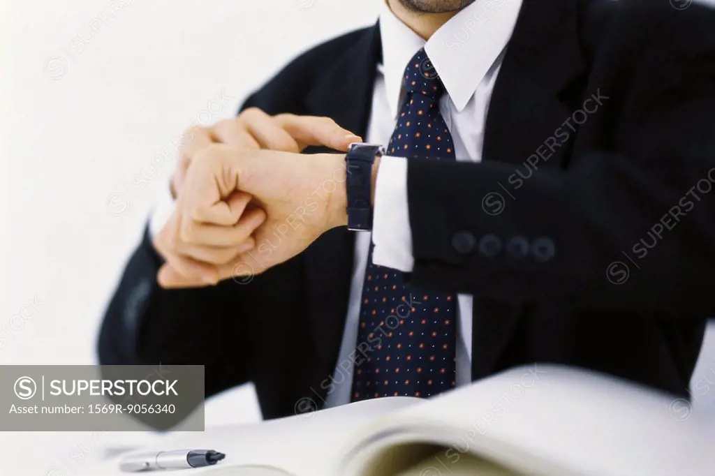 Businessman checking time on wristwatch, cropped