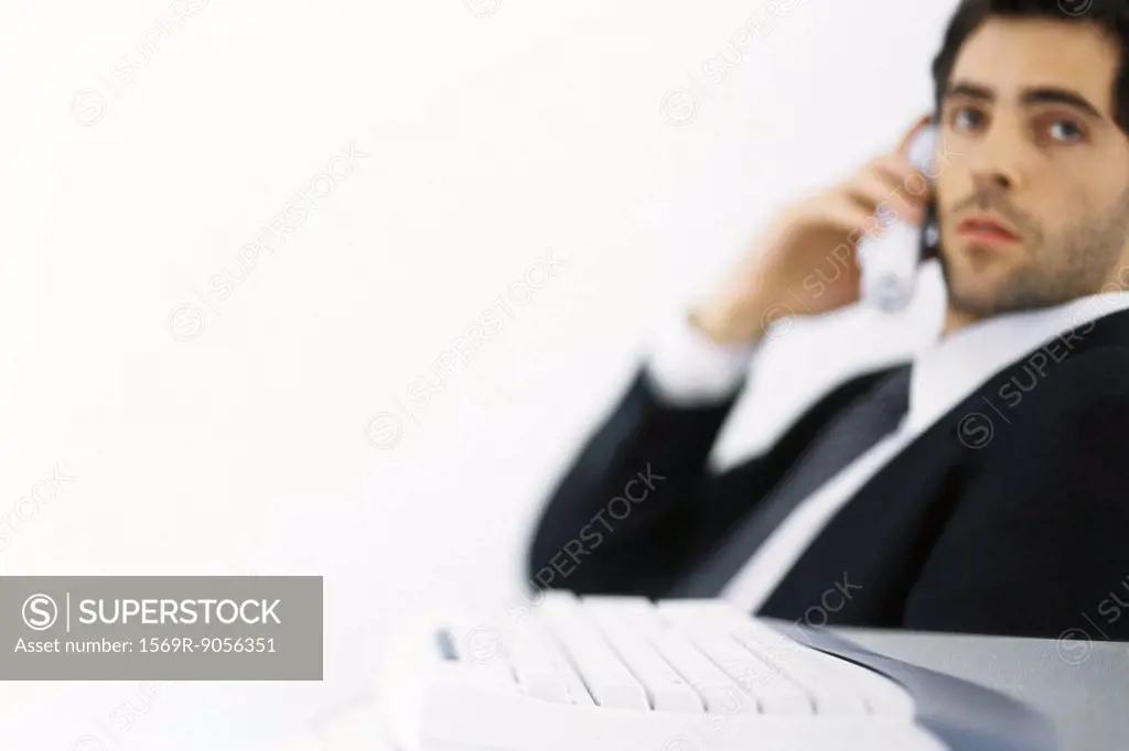 Businessman on phone call, looking away, keyboard in foreground