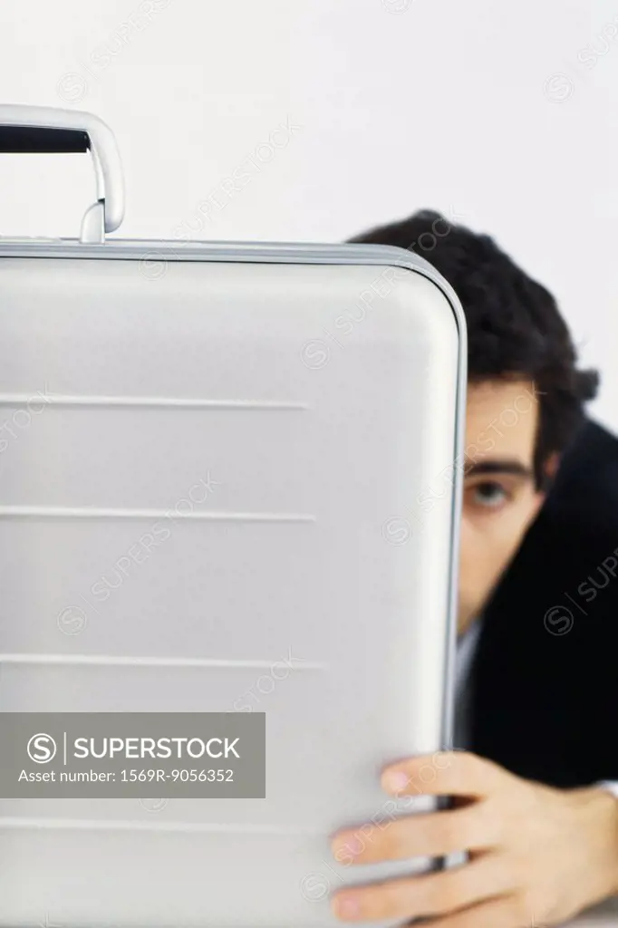 Businessman hiding behind briefcase