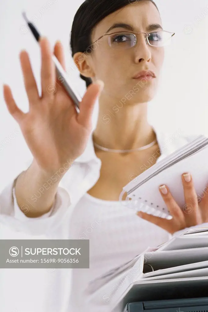 Woman with notepad, gesturing not to interrupt work