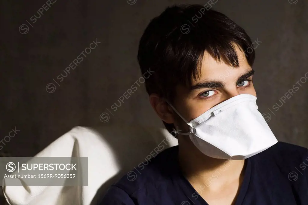 Teenage boy wearing flu mask, looking at camera