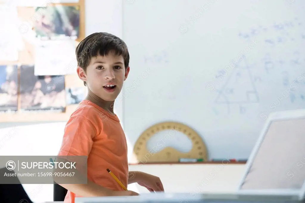 Elementary school student in classroom, looking over shoulder