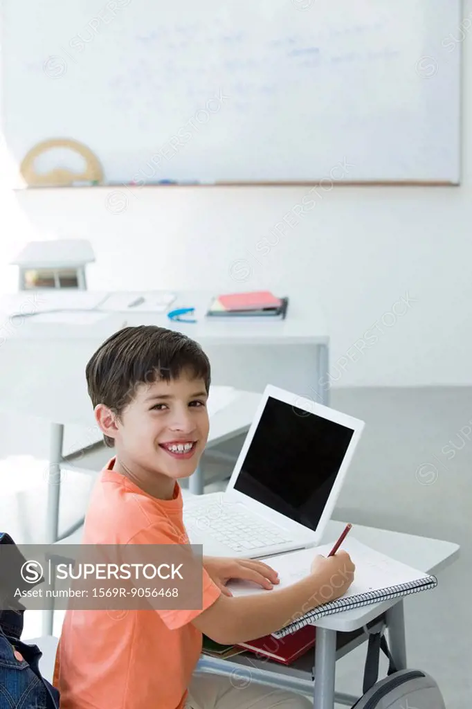 Elementary school student doing classwork, smiling at camera