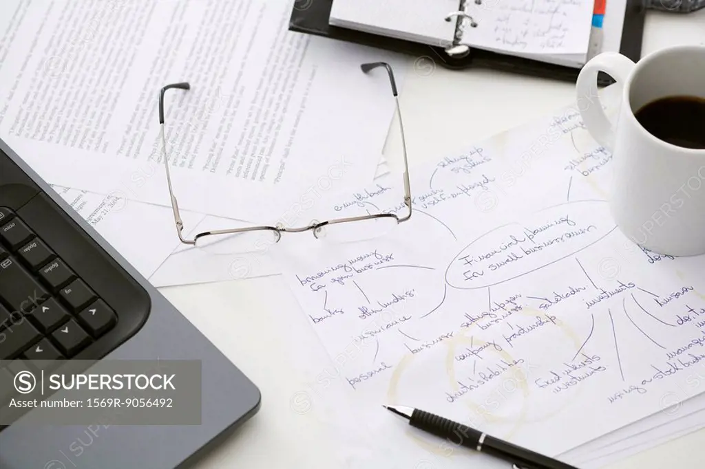 Hand written business plan on cluttered desk