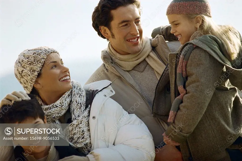 Family outdoors, father carrying daughter, mother ruffling son´s hair