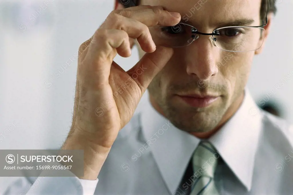 Young businessman adjusting glasses, portrait