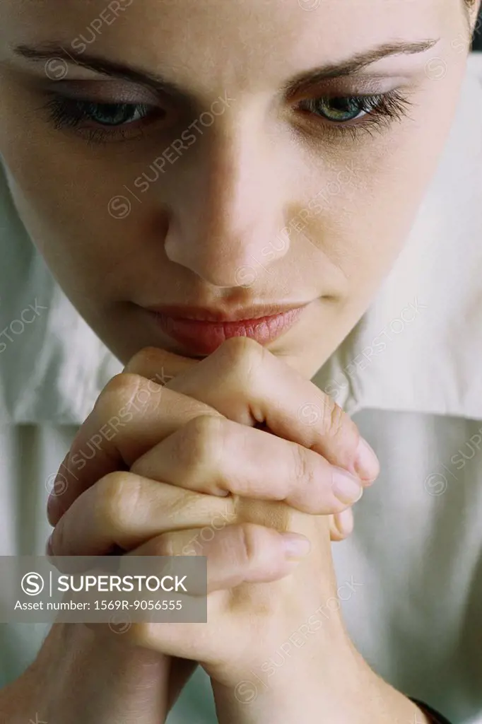 Woman with hands clasped in front of chin, close_up
