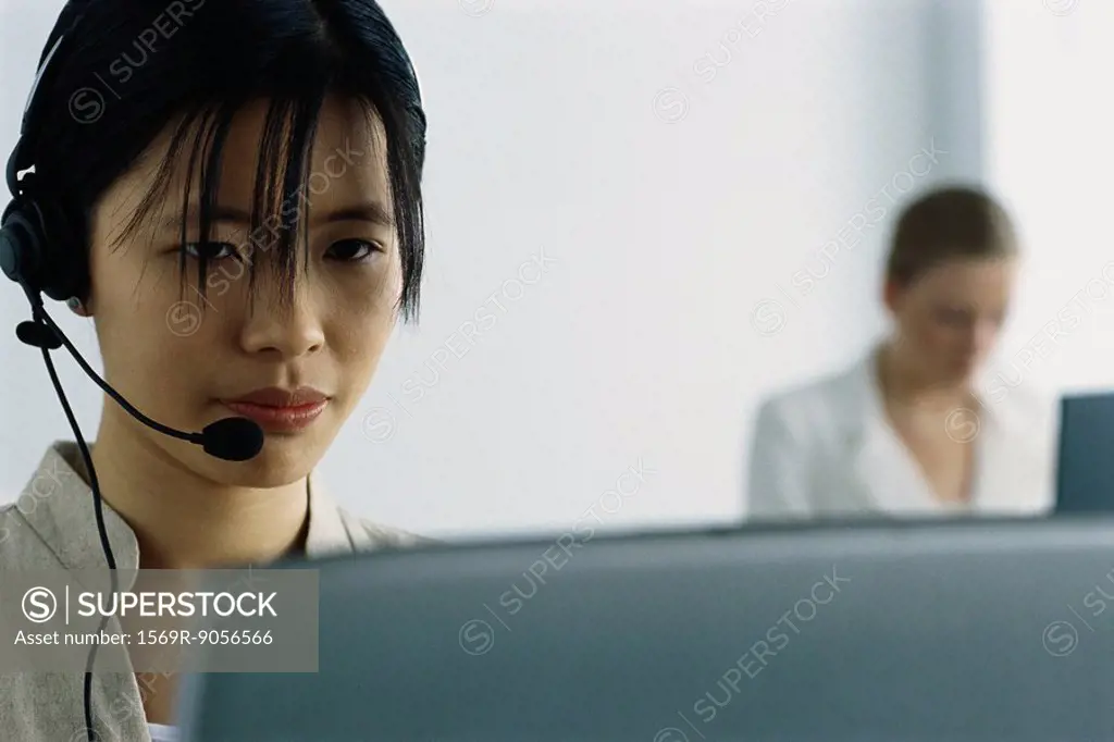 Young woman wearing headset and using computer
