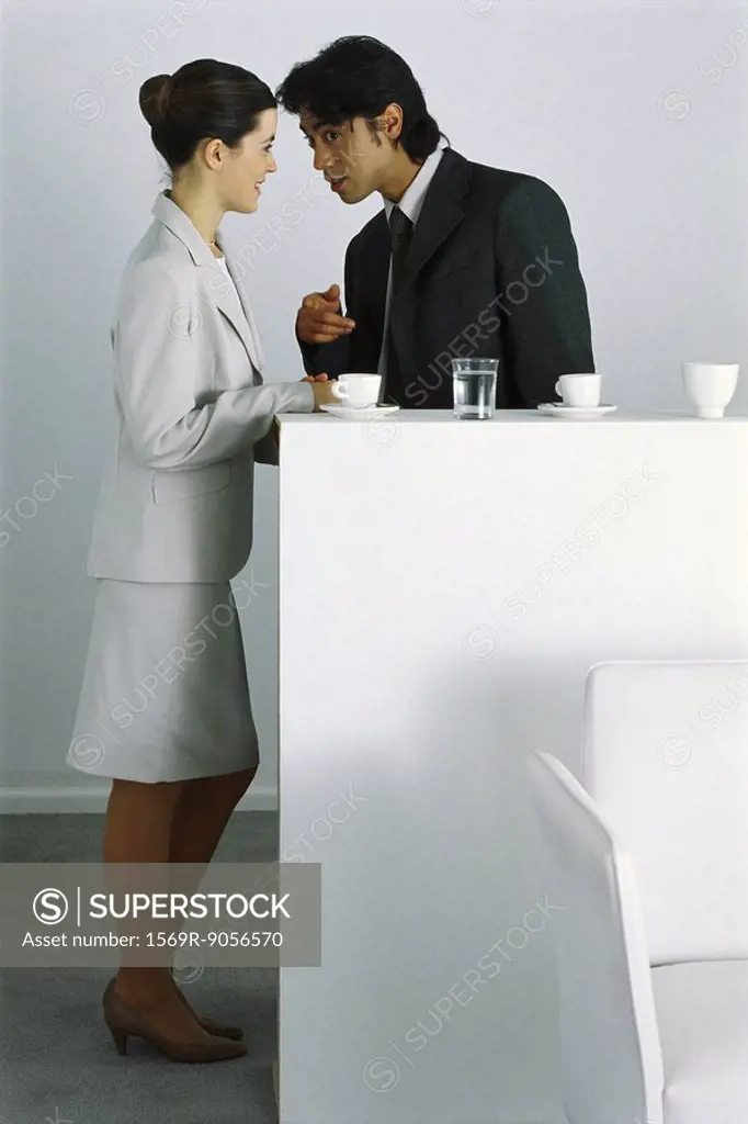 Male and female colleagues having coffee break together, gossiping