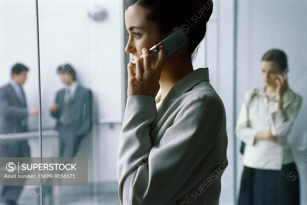 Businesswoman using cell phone in lobby, side view