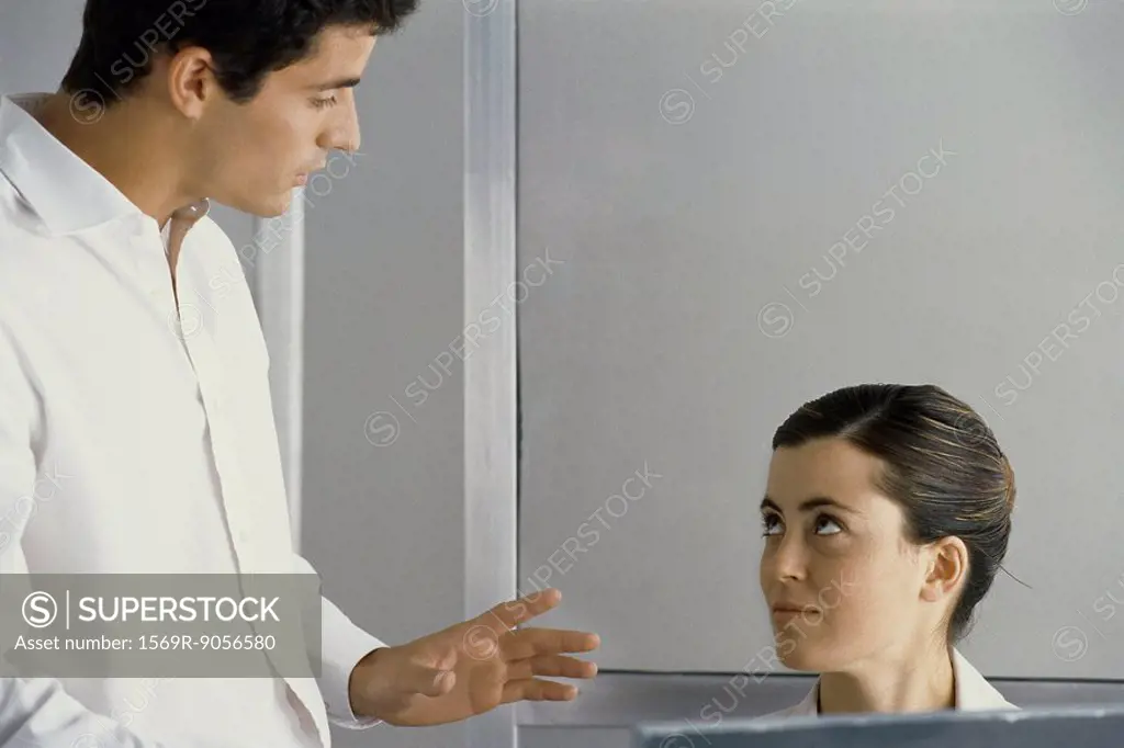 Man standing, talking to female colleague