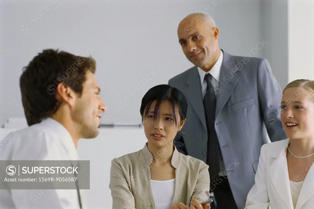 Four business associates having conversation, smiling