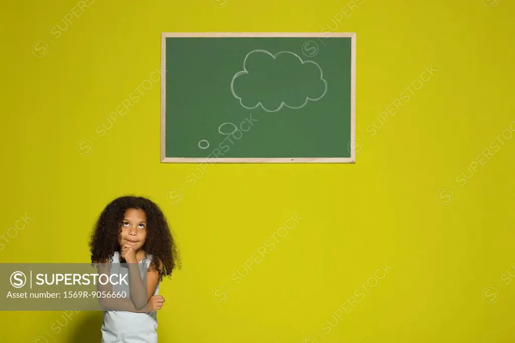Little girl thinking, empty thought bubble on chalkboard overhead
