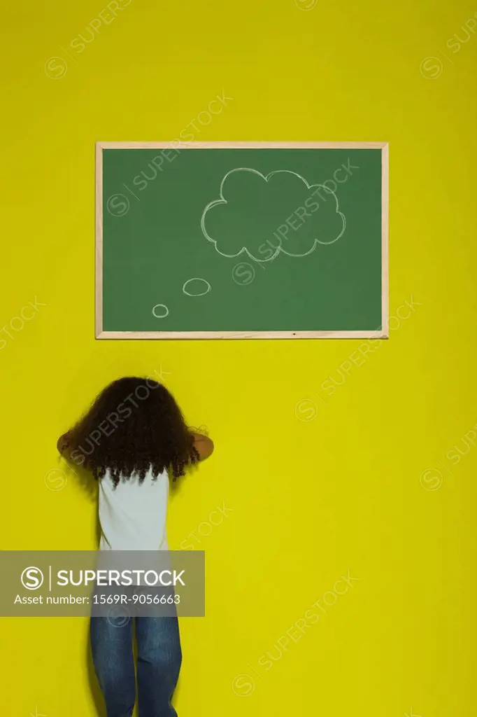 Little girl facing wall, thought bubble on chalkboard