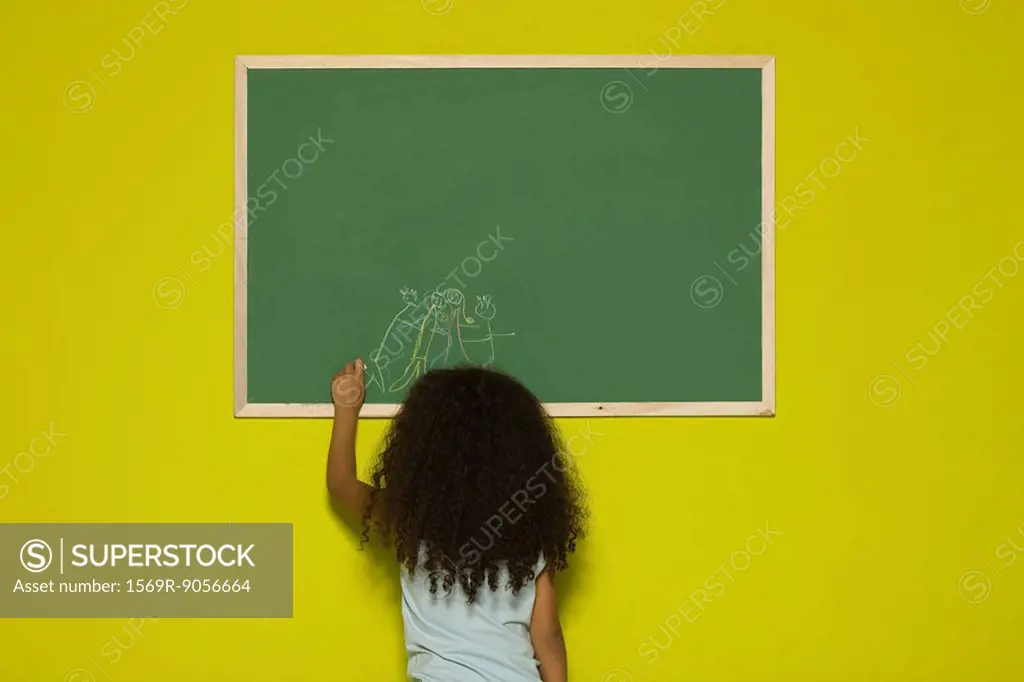 Little girl drawing on chalkboard, rear view