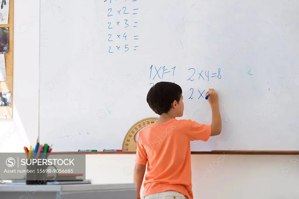 Elementary school student working math equations on whiteboard