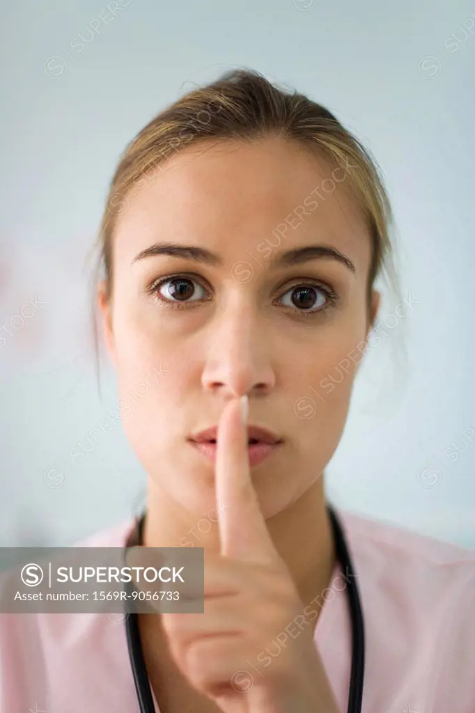 Nurse holding finger to lips, portrait