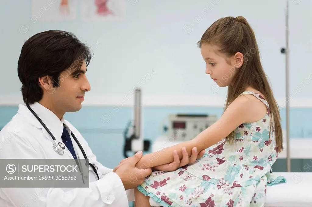 Pediatrician examining little girl´s arm