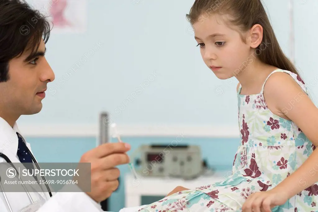 Pediatrician explaining syringe to little girl