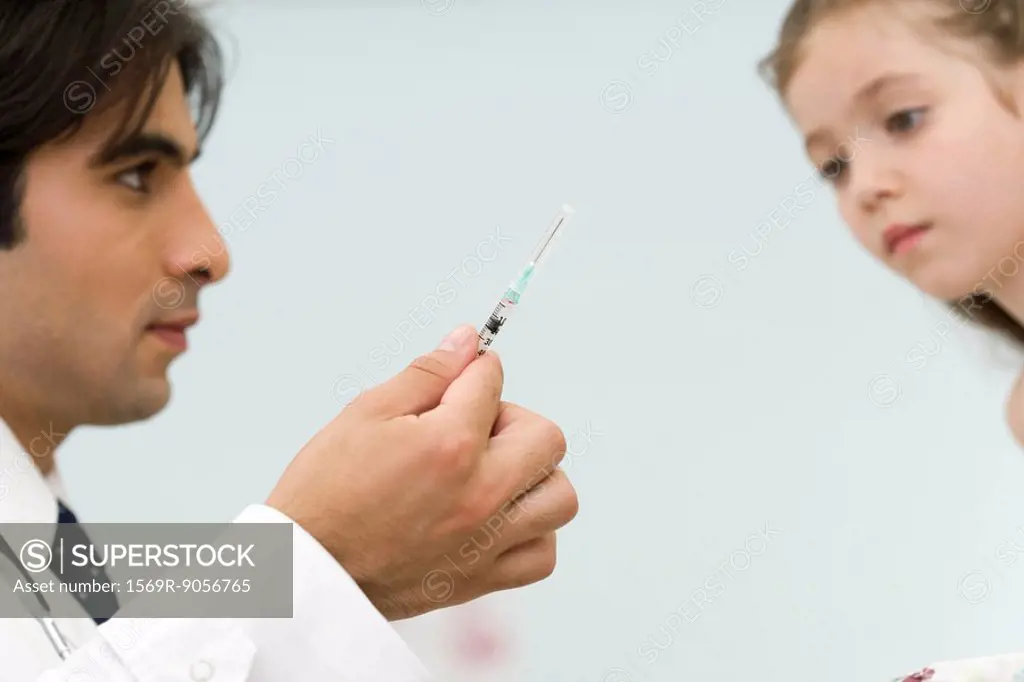 Pediatrician showing little girl syringe