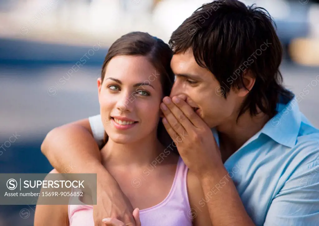Young man whispering into girlfriend´s ear
