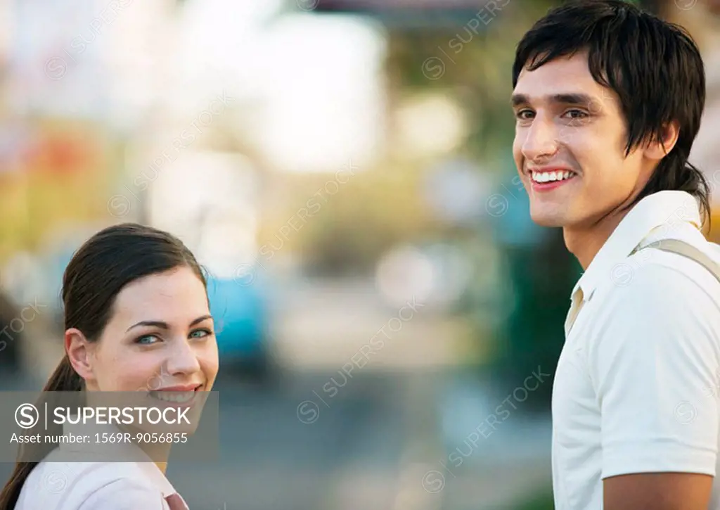 Young couple looking over shoulders, smiling