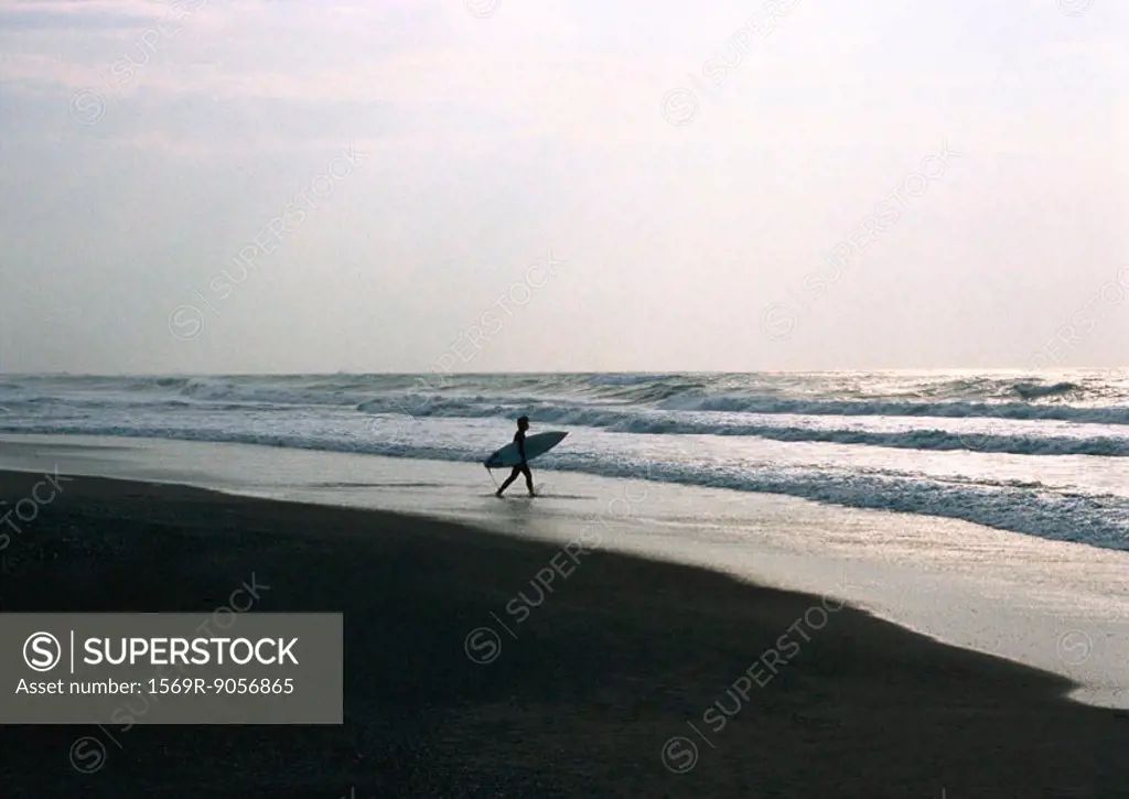 Surfer carrying surfboard out to waves