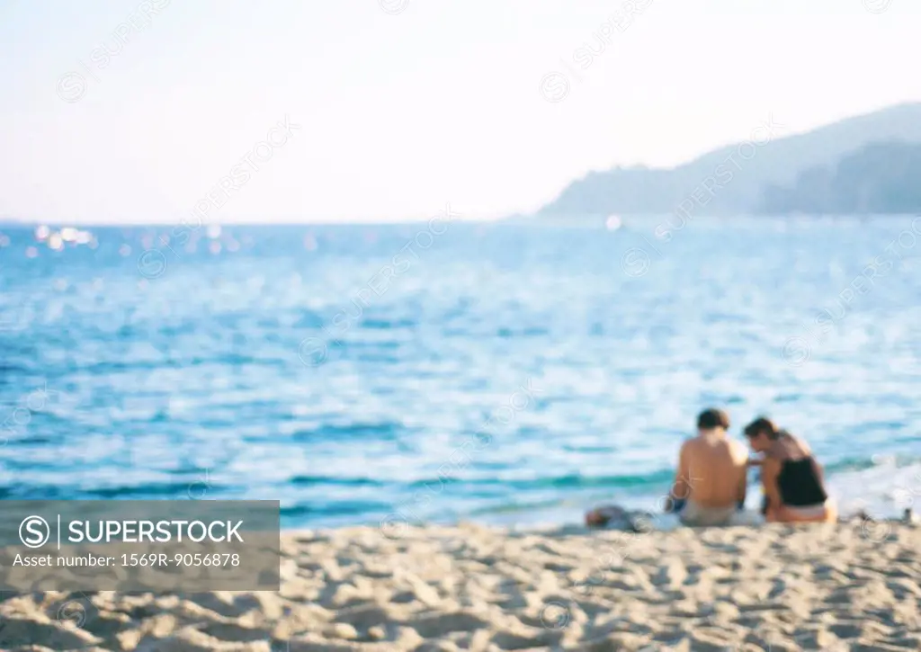 Two people sitting together on beach