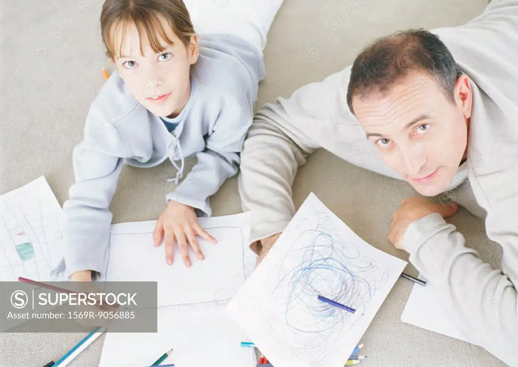Man and daughter lying on floor drawing together
