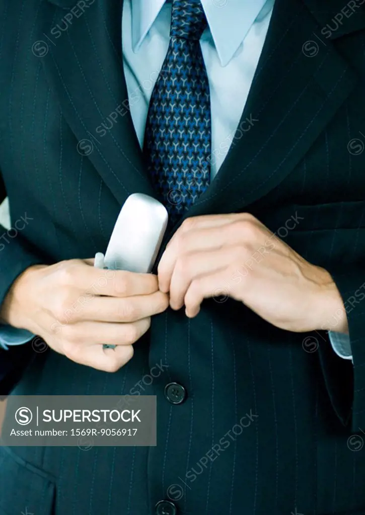 Businessman holding cell phone and buttoning jacket