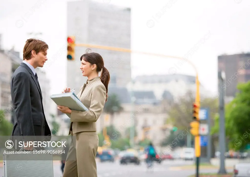 Young business associates standing on street corner, talking