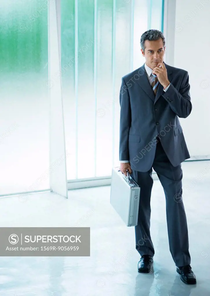 Businessman standing in lobby, holding briefcase