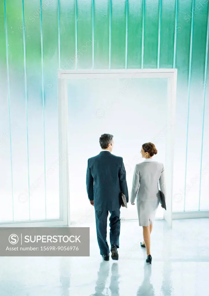 Male and female business partners leaving office building together