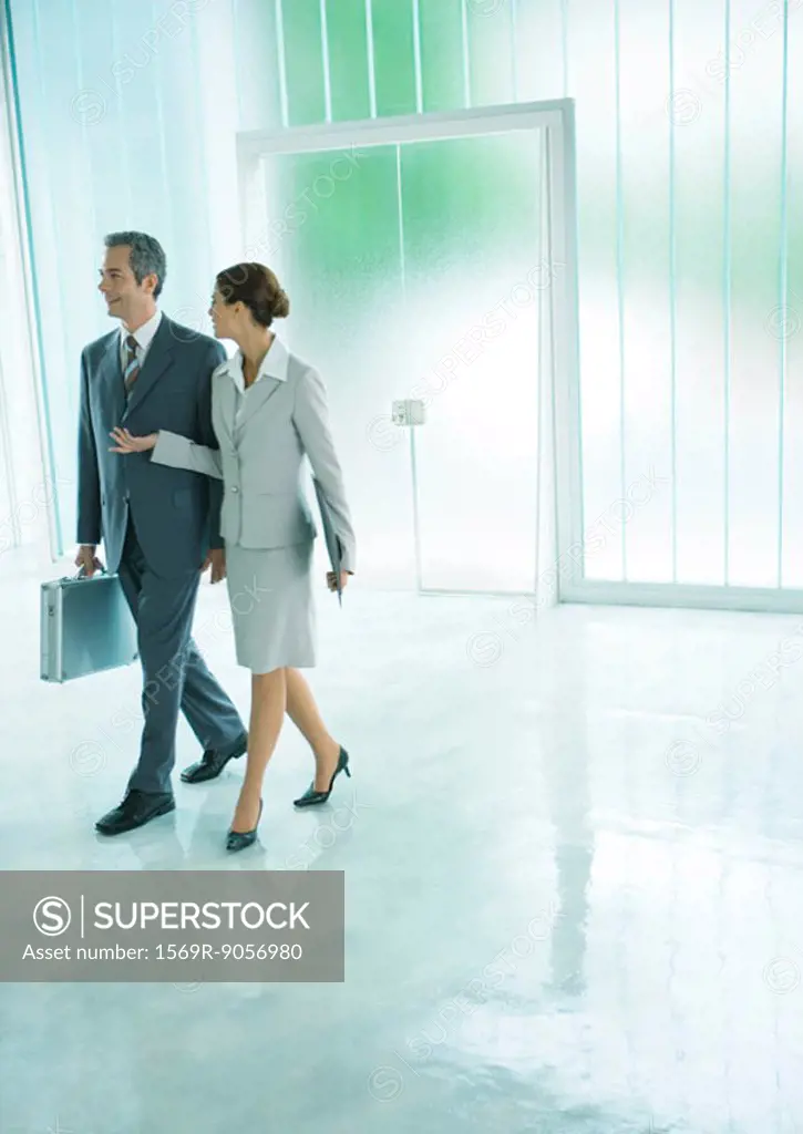 Female and male business associates walking through lobby